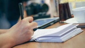Hand holding a pen and writing in a notebook